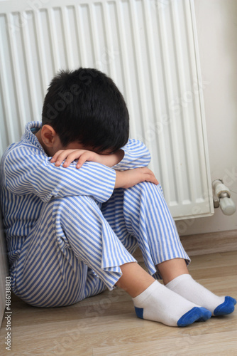 Sad boy sitting near wall.