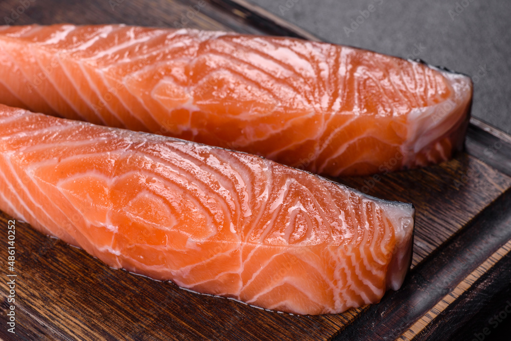 Fresh salmon fillets on black cutting board with herbs and spices Fresh salmon fillets on black cutting board with herbs and spices