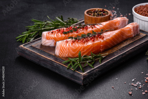 Fresh salmon fillets on black cutting board with herbs and spices