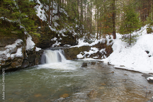 Small waterfall in winter mountain forest in snow