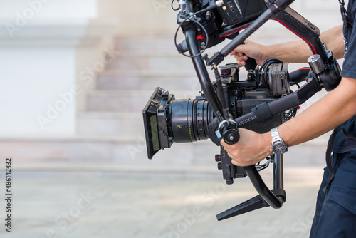 Movie shooting or video production and film crew team with camera equipment. Video camera operator working with equipment. Director of photography with a camera in his hands on the set.
