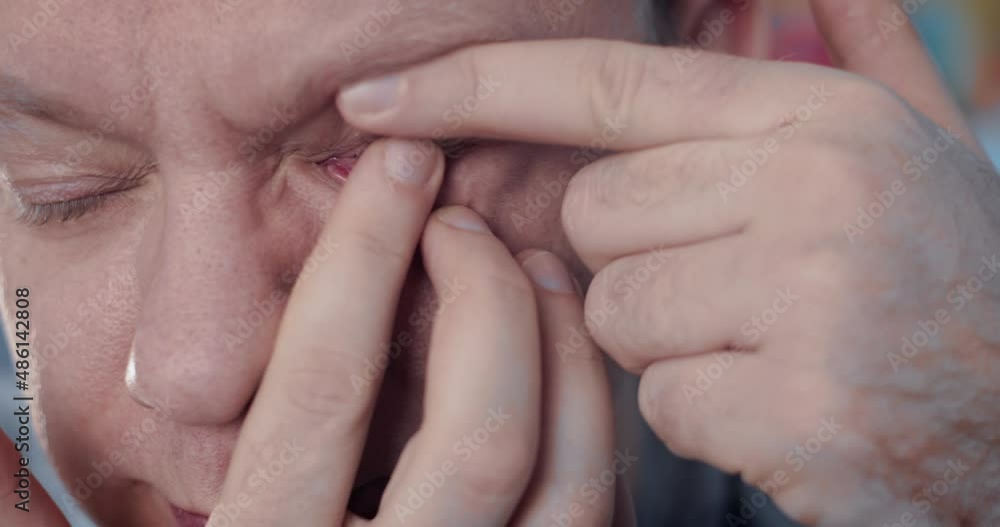 Man putting on the contact lens with fingers and blinking. Advertising of contact lenses for vision improvement. Optical shop, health care and medicine concept Man putting on the contact lens with fingers and blinking. Advertising of contact lenses for vision improvement. Optical shop, health care and medicine concept