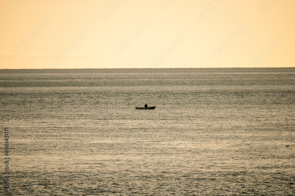Lonely fisherman sitting in his small fishing boat, trying to catch fish off the coast of Rovinj on the istrian peninsula, Croatia