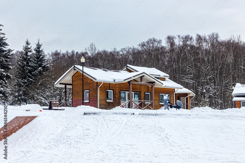 Wooden building made of cylindrical timber in the winter city park