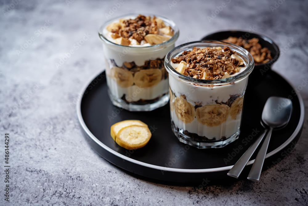 Banana Greek yogurt chocolate granola parfait in a glass Banana Greek yogurt chocolate granola parfait in a glass