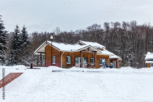 Wooden building made of cylindrical timber in the winter city park © roundex
