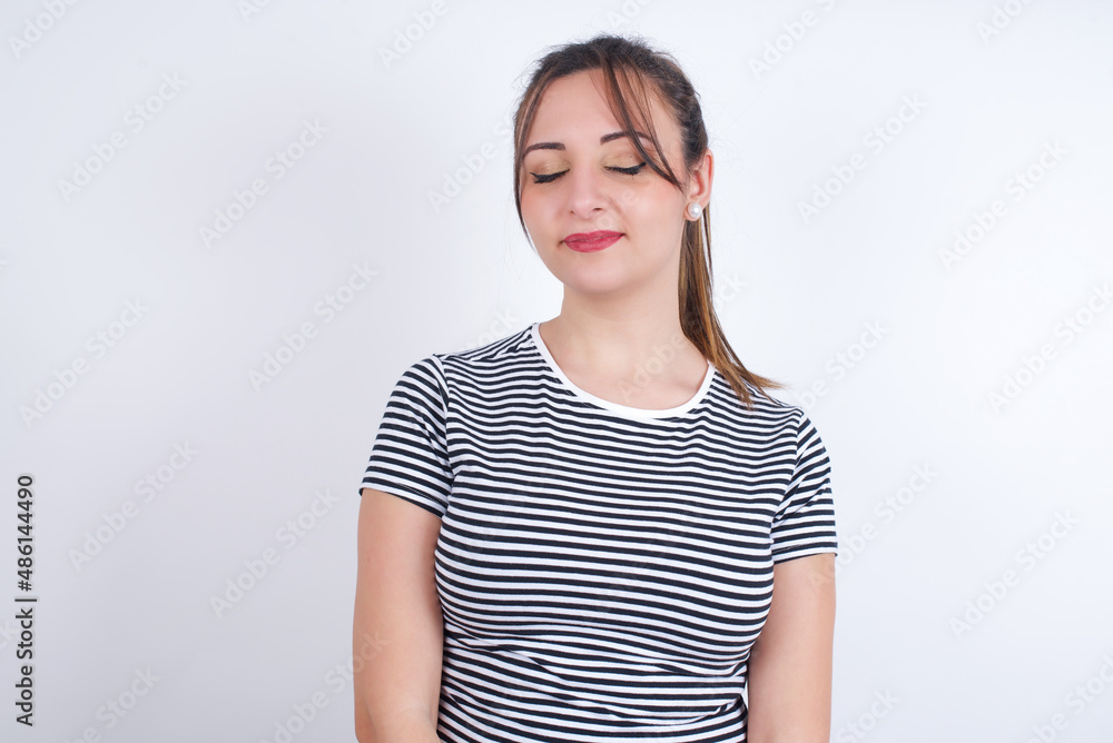 young Arab woman wearing striped t-shirt over white background nice-looking sweet charming cute attractive lovely winsome sweet peaceful closed eyes young Arab woman wearing striped t-shirt over white background nice-looking sweet charming cute attractive lovely winsome sweet peaceful closed eyes