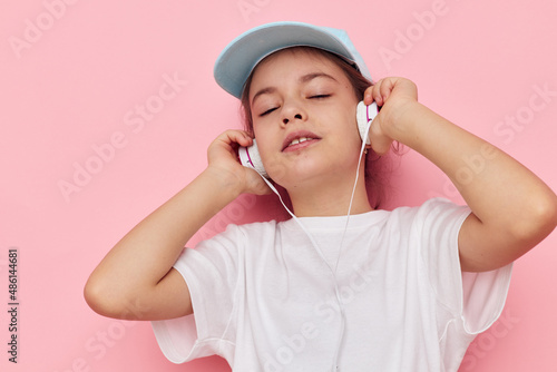 little girl listening to music on headphones isolated background