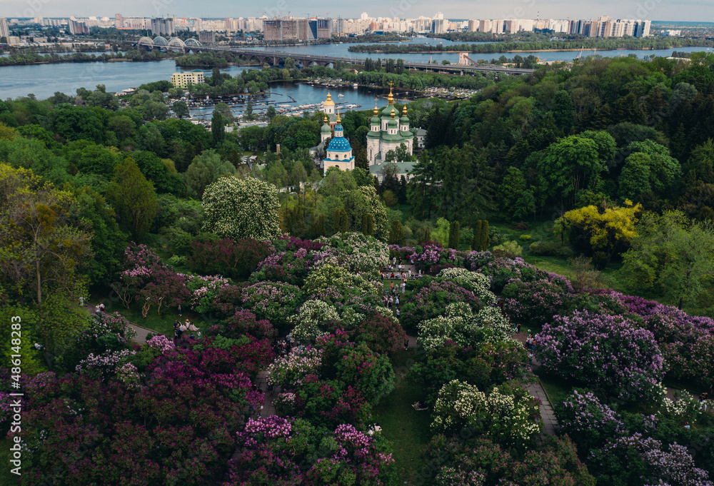 panorama beautiful top view of Kiev beautiful green park with purple flowers church near the river with a bridge on the city background on a sunny day, overall plan