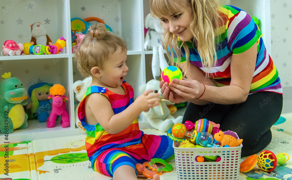 Baby plays in the room with her mother. Selective focus. Baby plays in the room with her mother. Selective focus.