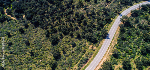 Empty long mountain road to the horizon on a sunny summer day at bright sunset - aerial drone shot