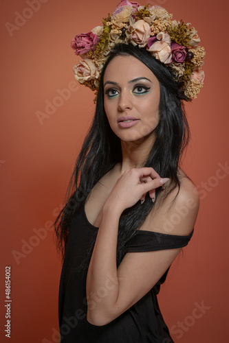 Hairstyle and Make up - beautiful female art portrait with wreath of roses, studio. Elegance. Genuine brunette, creative hairstyle with flowers. Portrait of a attractive woman with beautiful eyes.