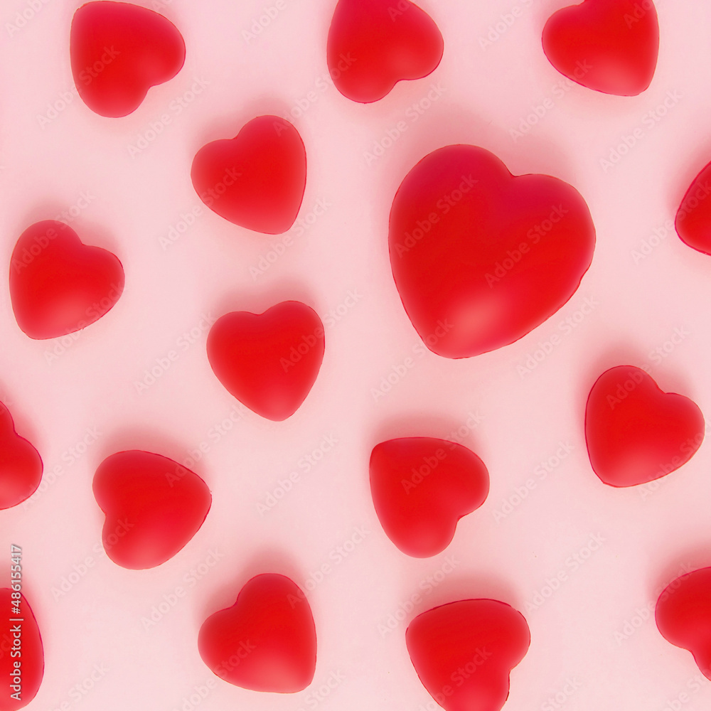 Red hearts pattern with one big red heart on pink backgrounds. Symbol of love, affection, anniversary. A minimal concept of happiness, fulfillment, togetherness. Valentine's Day.