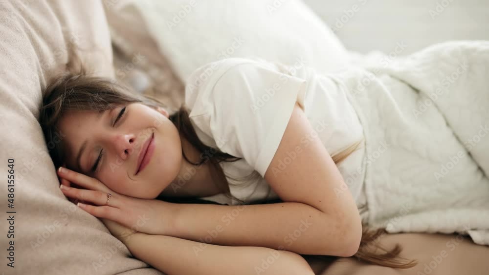 Happy smiling young woman sleeping in bed. Positive pretty girl enjoying sleeping in cozy bedroom. Cute girl. High quality 4k footage Happy smiling young woman sleeping in bed. Positive pretty girl enjoying sleeping in cozy bedroom. Cute girl. High quality 4k footage