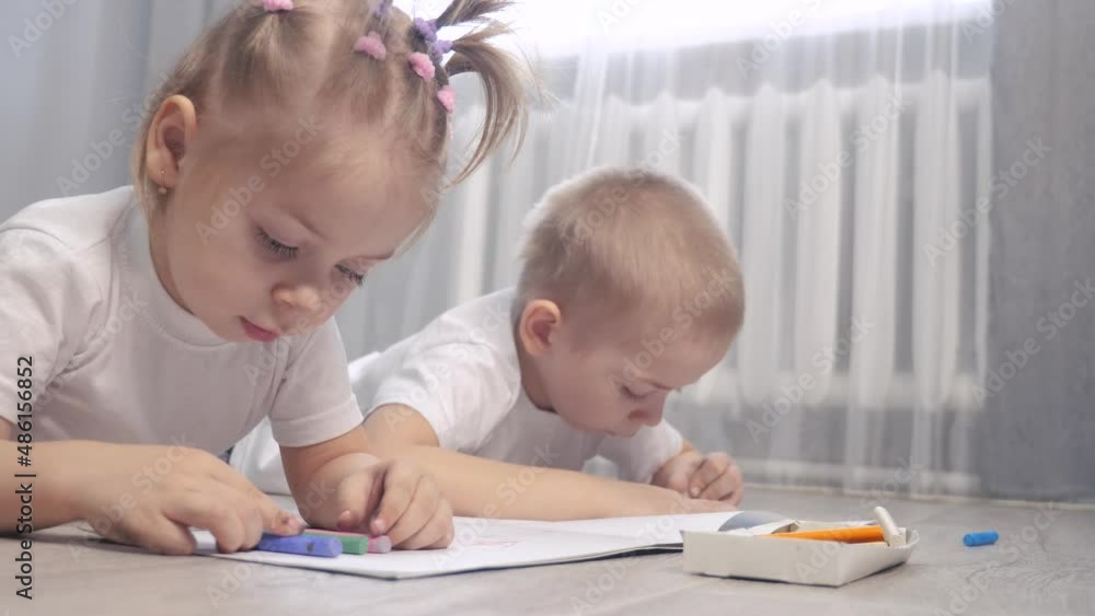 happy family brother and sister teamwork concept. little boy and girl draw on floor in a sketchbook. brother and sister in the room draw lifestyle with crayons happy family brother and sister teamwork concept. little boy and girl draw on floor in a sketchbook. brother and sister in the room draw lifestyle with crayons
