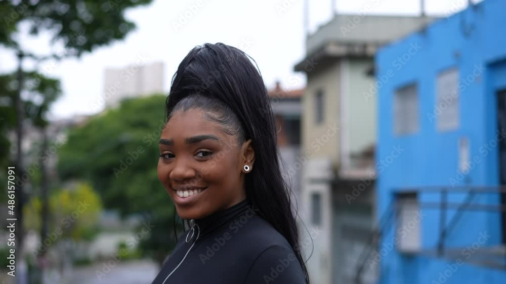 A Brazilian girl turning head to camera smiling while walking in street A Brazilian girl turning head to camera smiling while walking in street