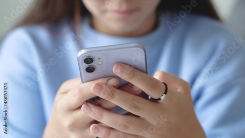 Pretty teenage girl student using texting smartphone or chat, Womans hands holding phone , typing message on mobile in the living room at home morning. Close up view. 4k footage