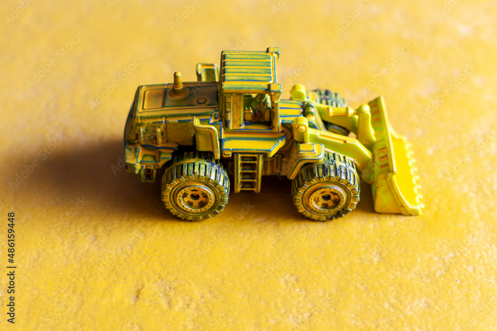 Obraz premium yellow toy bulldozer on yellow background