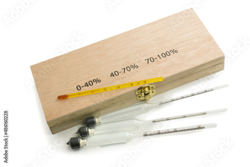 Three hydrometers for measuring degree of alcohol and thermometer in white background