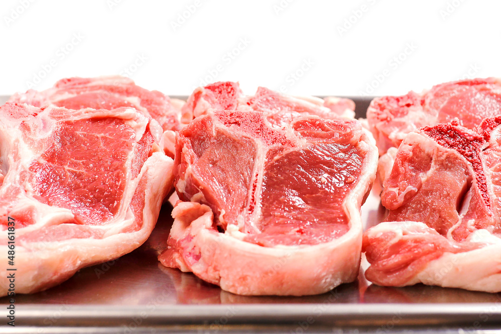 Stack of fresh lamb loin chops. Close up. Meat industry. The product is on a metal tray, Butcher craft. Stack of fresh lamb loin chops. Close up. Meat industry. The product is on a metal tray, Butcher craft.