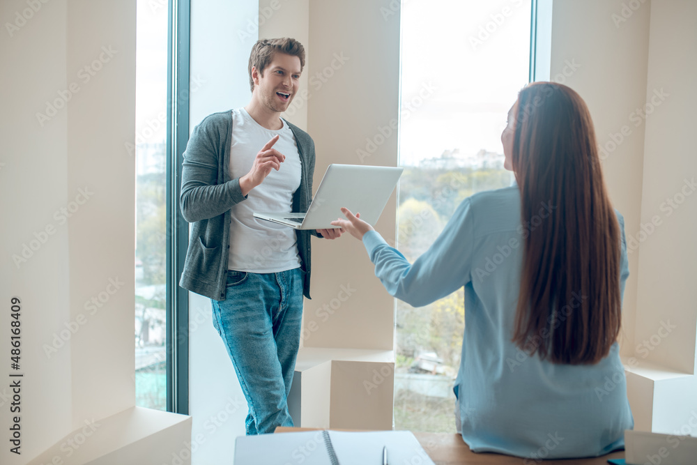 Obraz premium Man with laptop and woman talking in office