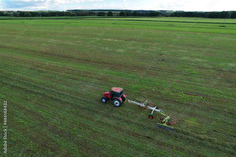Tractor raking grass for silage harvesting. Agriculture farm machinery work at field. Cutting grass silage at farm field. Wheel Rakes for Grass silage raking, baling, wrapping. Hay making for cattle.
Tractor raking grass for silage harvesting. Agriculture farm machinery work at field. Cutting grass silage at farm field. Wheel Rakes for Grass silage raking, baling, wrapping. Hay making for cattle.