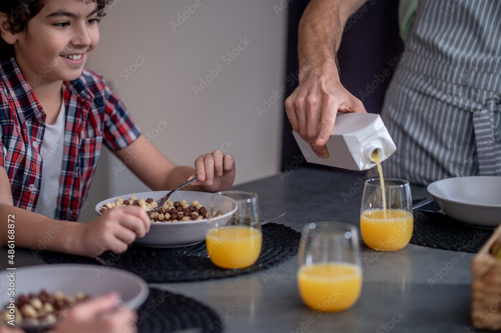 Boy looking at mans hand pouring juice Boy looking at mans hand pouring juice