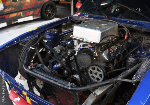 Sports car engine with turbine. An open race car hood on a pit stop while racing on a race track. Motor with turbocharger. Boos and tunning.