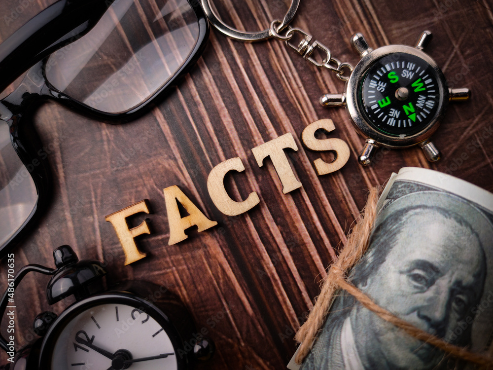 Top view glasses,clock,bankotes,compass and wooden word with text FACTS on a wooden background. Top view glasses,clock,bankotes,compass and wooden word with text FACTS on a wooden background.