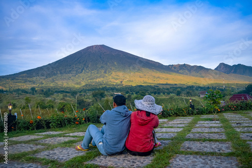 Back view of couple sitting enjoying looking at beautiful scenery of rinjani mountain