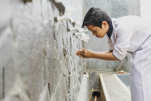 A boy performs ablution before praying at the mosque