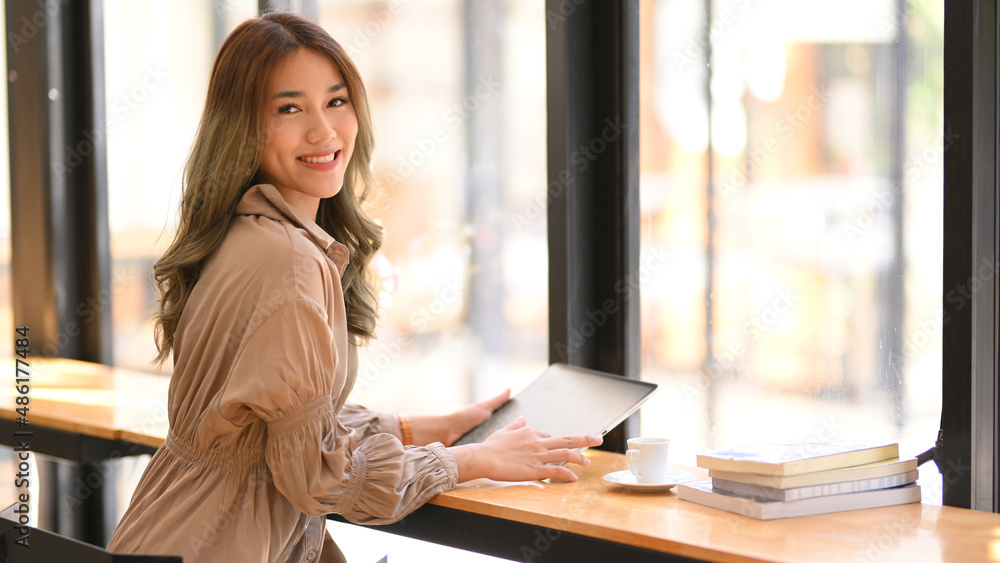 Obraz premium Businesswoman sitting in a co-working space, using tablet.