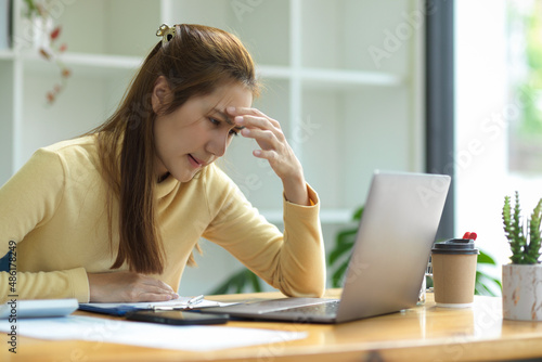 A stressed-out businesswoman sits in front of her laptop screen