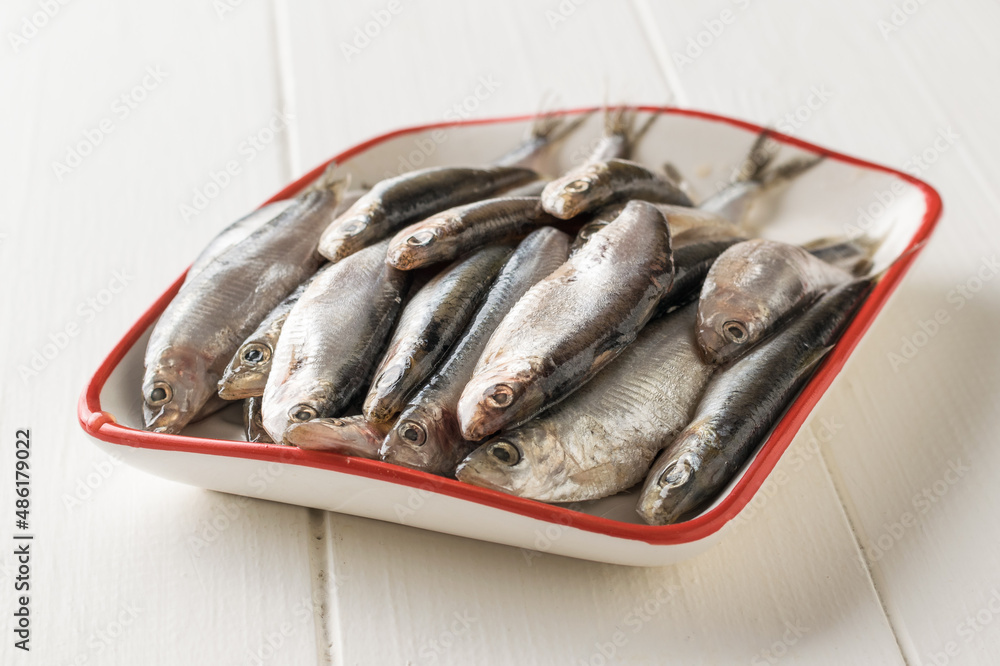 Salted sprat in a white plate with a red border. Salted sprat in a white plate with a red border.