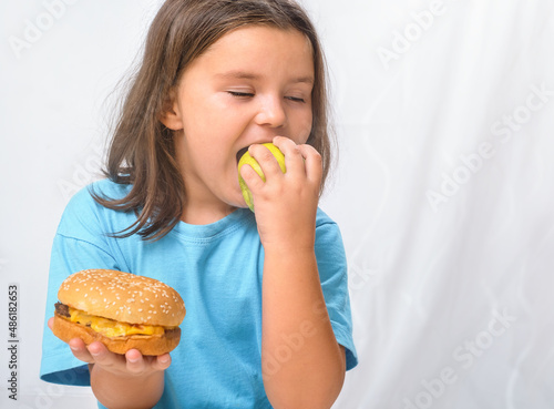 Child girl biting an apple instead of a hamburger