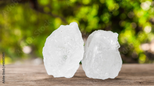 Crystal clear alum cubes or Potassium alum on brown wood plank. Chemical compound substance. Concept for beauty , spa and underarm treatment industrial.  photo