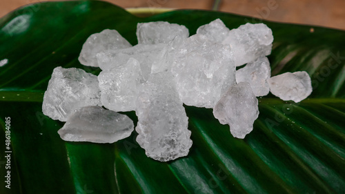 Crystal clear alum cubes or Potassium alum on green leaf. Chemical compound substance. Concept for beauty , spa and underarm treatment industrial.  photo