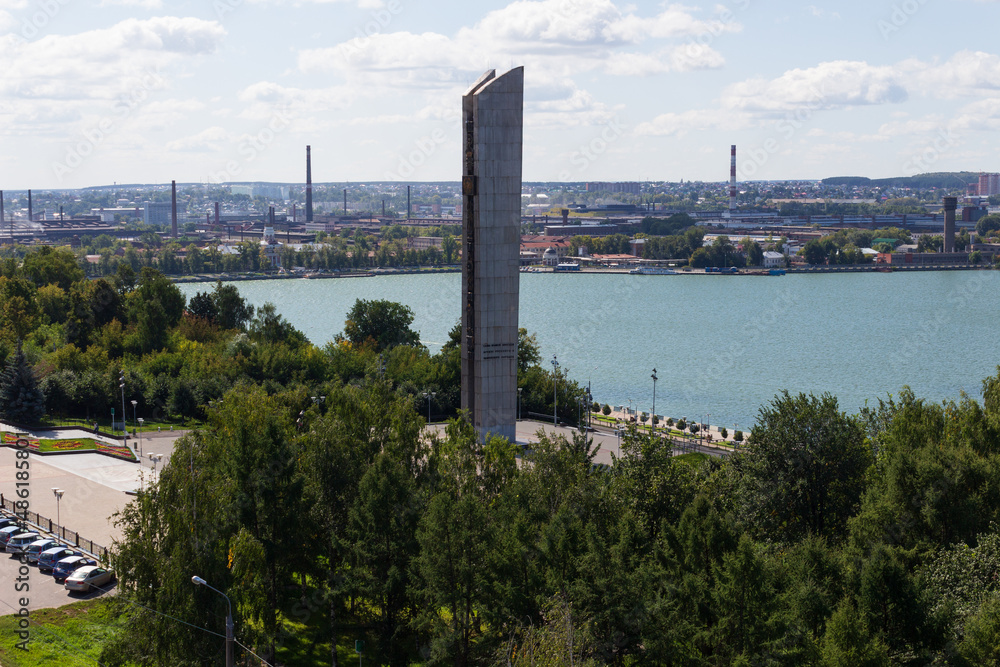 Obraz premium summer embankment of the city of Izhevsk, a stele on the alley of the pond, the urban environment from a height