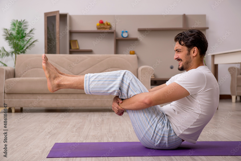 Fototapeta premium Young man doing sport exercises at home