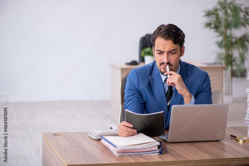 Young male employee unhappy with excessive work in the office Young male employee unhappy with excessive work in the office