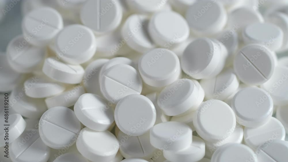 The medicine concept.white medical pills rotating closeup. Pills and drugs. Pharmaceutical Industry.many white round pills. pharmaceutical production. drugs on the production line. moving background The medicine concept.white medical pills rotating closeup. Pills and drugs. Pharmaceutical Industry.many white round pills. pharmaceutical production. drugs on the production line. moving background