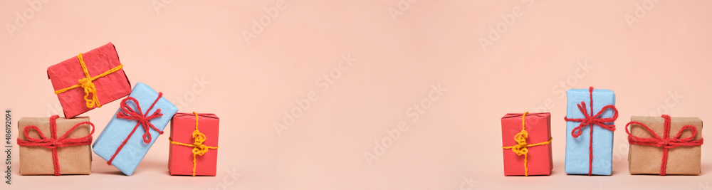 Fototapeta premium Banner, gifts packed in multicolored paper on pastel beige background.Concept Christmas holidays and eighth March in spring.