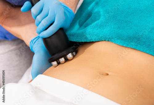 Closeup of needleless mesotherapy hardware procedure to reduce body fat and tighten skin on female belly in aesthetic clinic © JackF