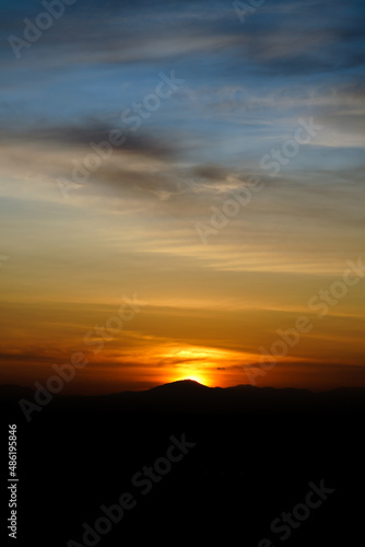 Shilhouette mountain in sunset sky with clouds.