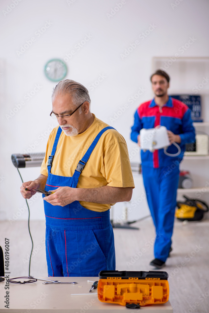 Two male repairmen working at workshop Two male repairmen working at workshop
