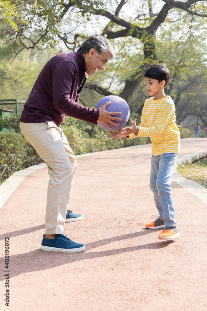 Father and son playing with ball at park
