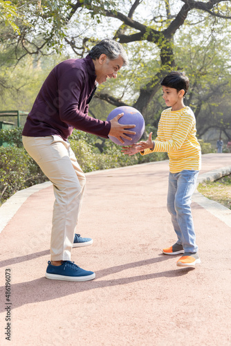 Father and son playing with ball at park  © G-images