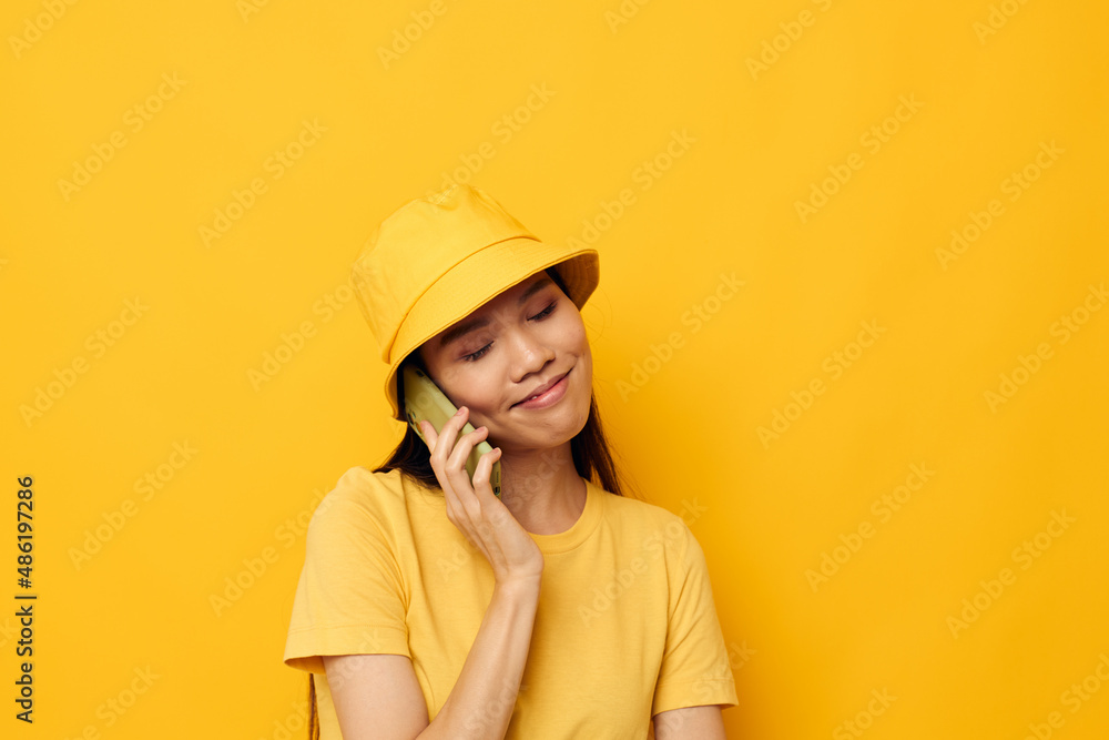 Portrait Asian beautiful young woman in a yellow hat and T-shirt talking on the phone Lifestyle unaltered Portrait Asian beautiful young woman in a yellow hat and T-shirt talking on the phone Lifestyle unaltered