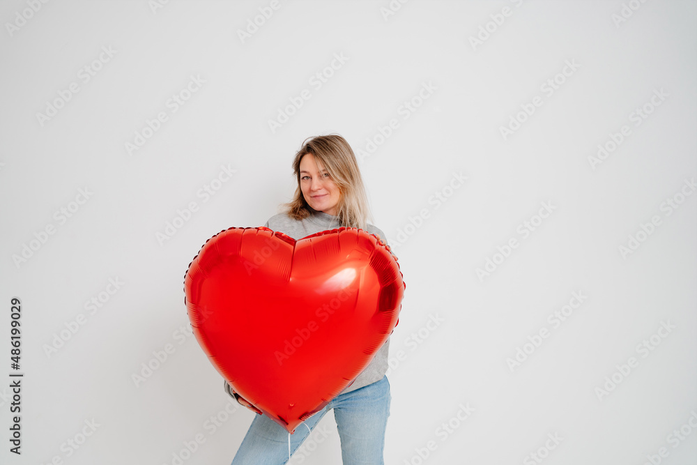 an blonde woman with a large red heart-shaped balloon on a white background. valentine's day an blonde woman with a large red heart-shaped balloon on a white background. valentine's day