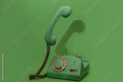 Green old retro vintage phone with handset up. Minimalistic, monochromatic composition
